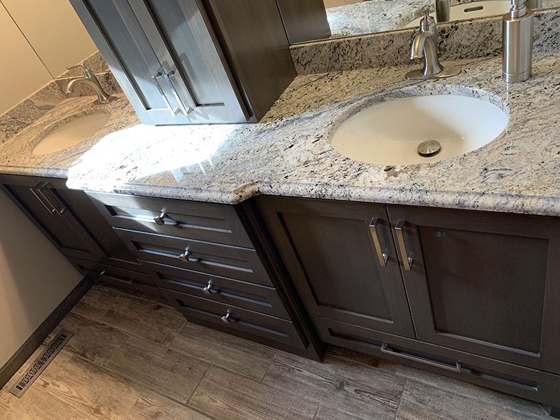 double sink Granite bathroom counter top with dark brown cabinets and drawers 