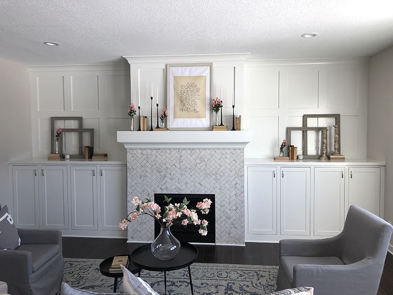 Living area showing a custom fireplace mantel and cabinets adorned with several picture frames and flowers